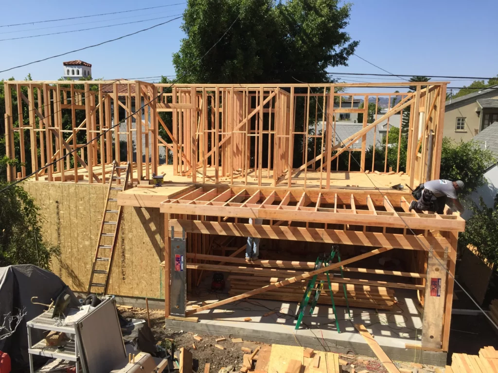 Wooden house framing construction with workers on site.