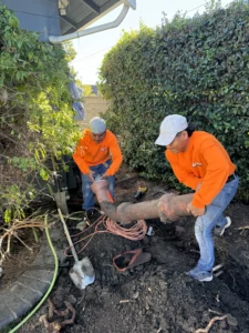 Workers repairing underground pipes outdoors.