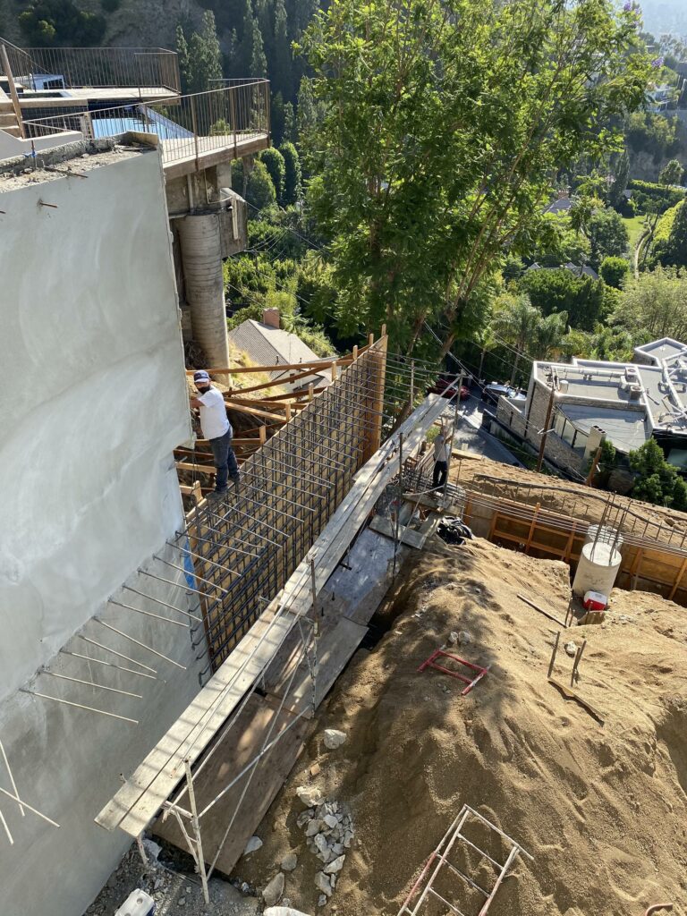 Construction workers reinforcing a hillside concrete wall.