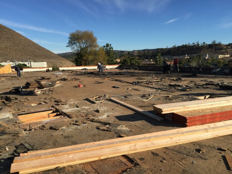 Workers at construction site with materials and debris.
