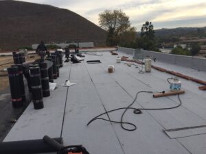 Workers installing roofing materials on commercial building.