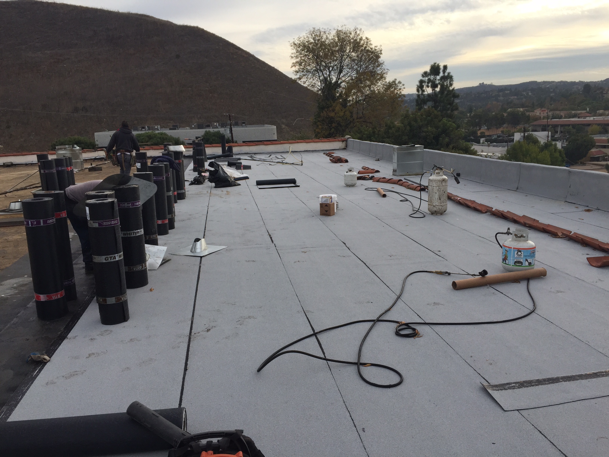 Workers installing roofing materials on commercial building.
