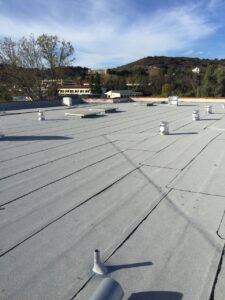 Flat commercial rooftop with ventilation pipes and clear sky.