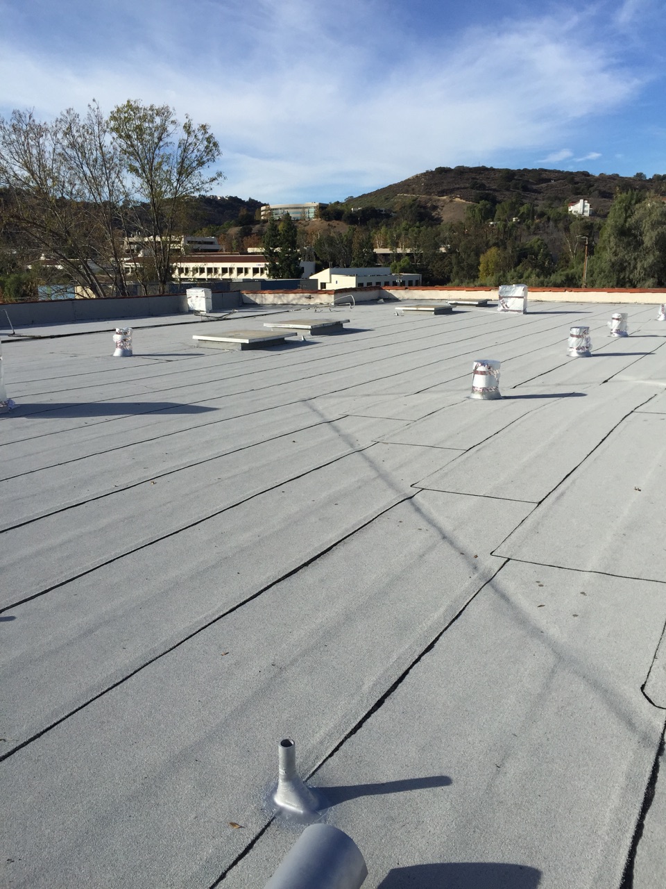 Flat commercial rooftop with ventilation pipes and clear sky.