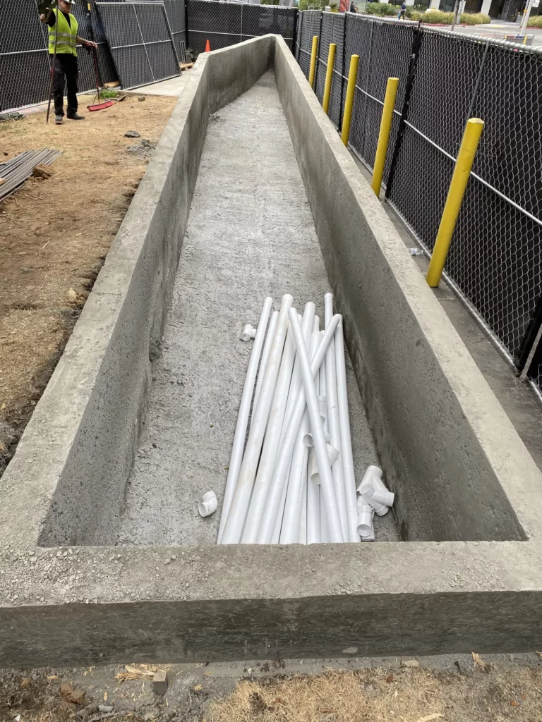 Concrete trench with pipes at construction site.