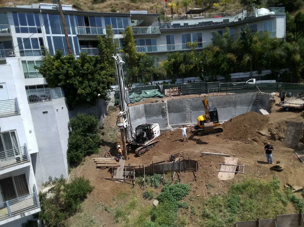 Construction site with machinery and workers near buildings.