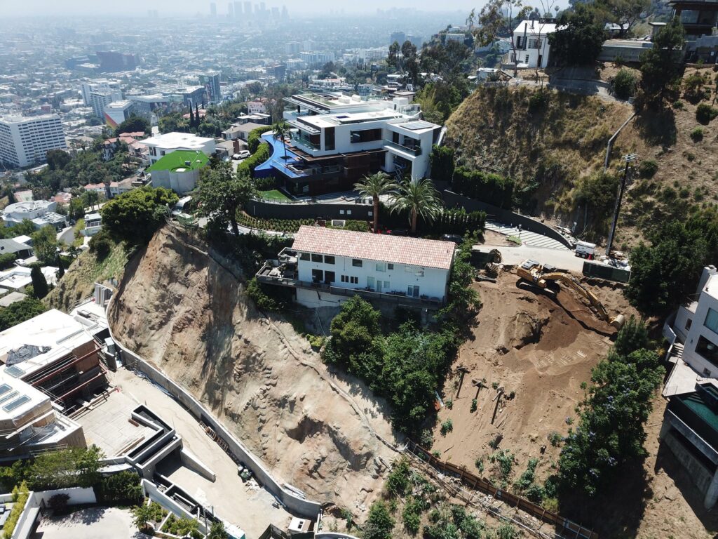 Aerial view of hillside construction site near luxury homes.