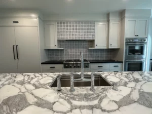 Modern kitchen with marble countertops and stainless steel appliances.