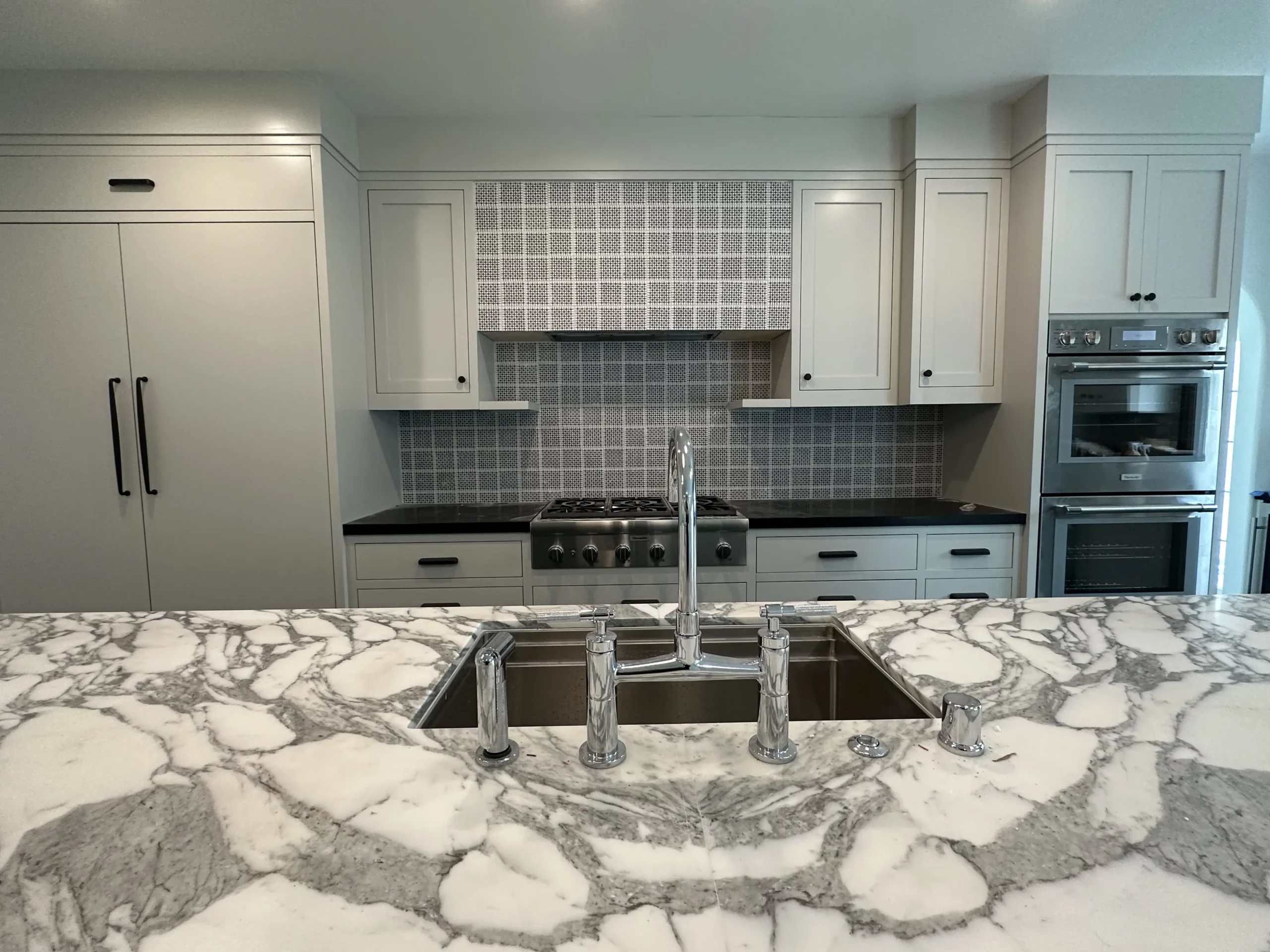 Modern kitchen with marble countertops and stainless steel appliances.
