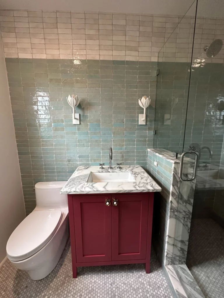 Modern bathroom with tiled walls and red vanity.