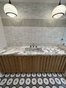 Modern bathroom with marble sink and patterned floor tiles.