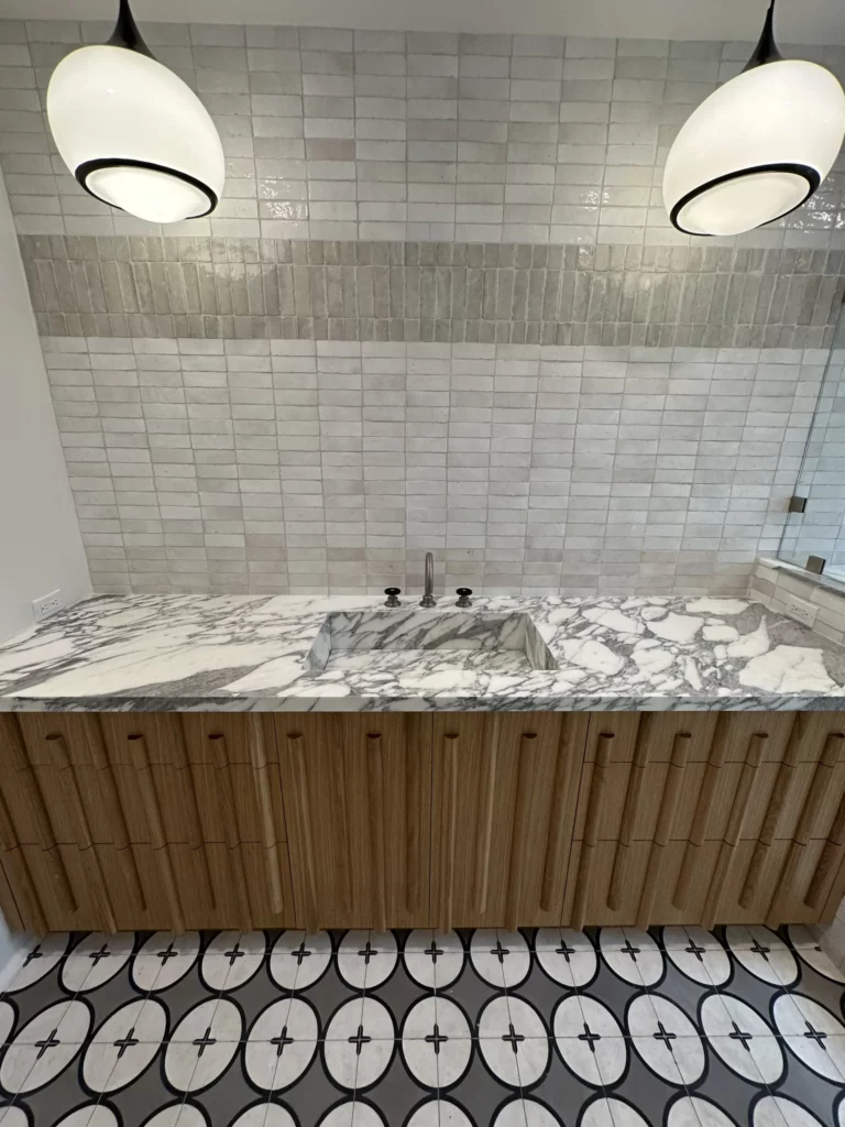 Modern bathroom with marble sink and patterned floor tiles.