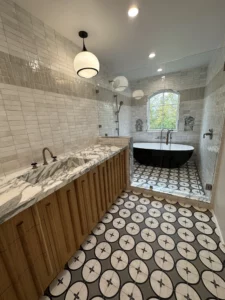 Modern bathroom with black freestanding tub and patterned floor.