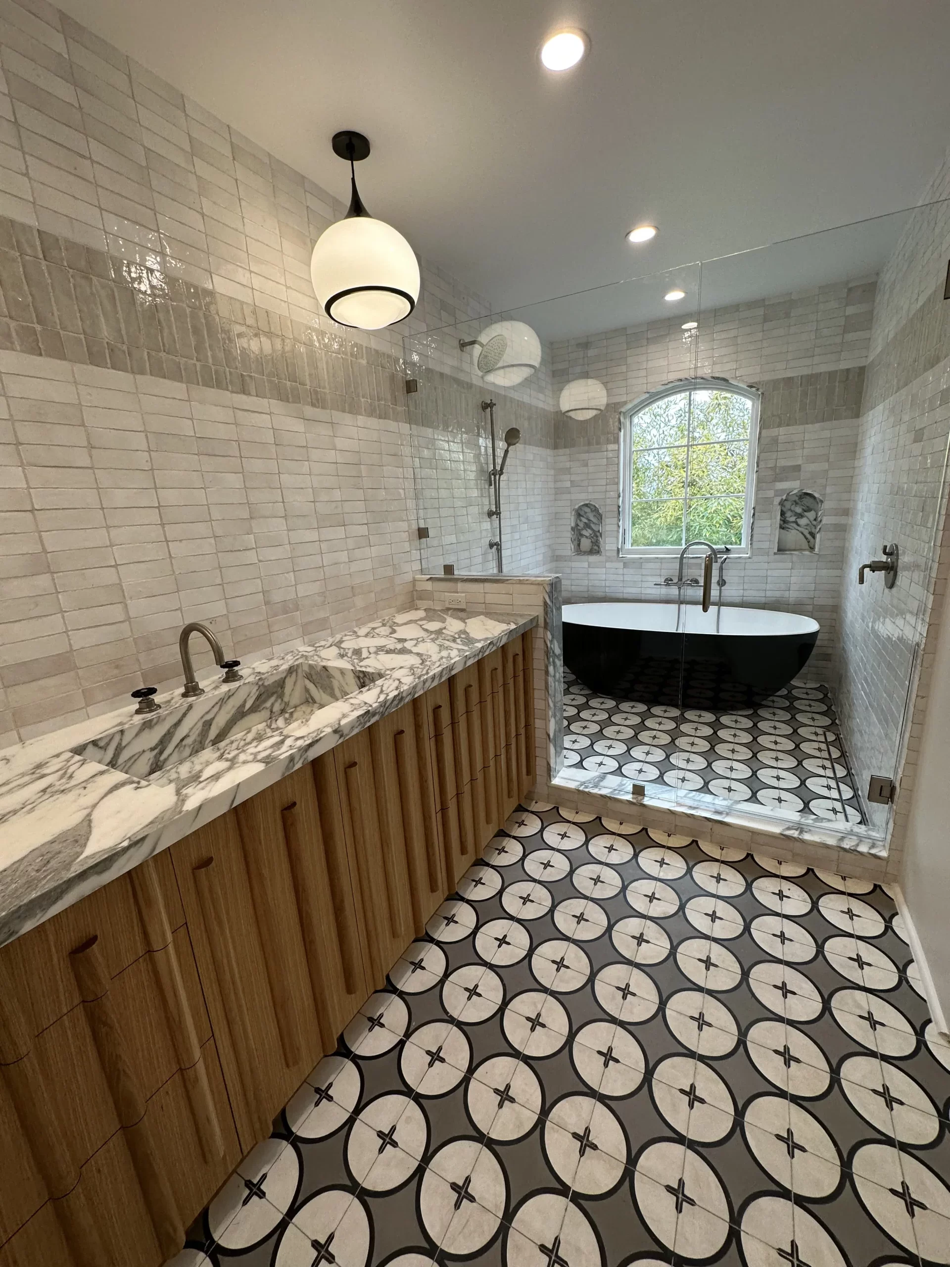 Modern bathroom with black freestanding tub and patterned floor.