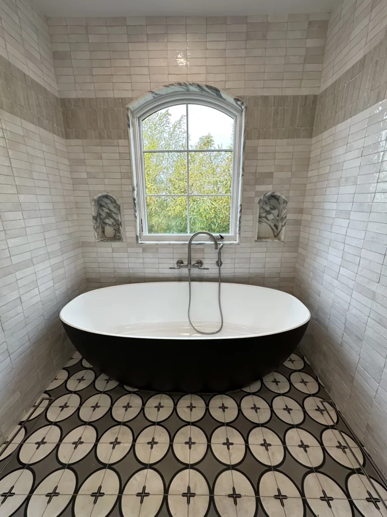 Elegant bathroom with freestanding tub and patterned floor tiles.