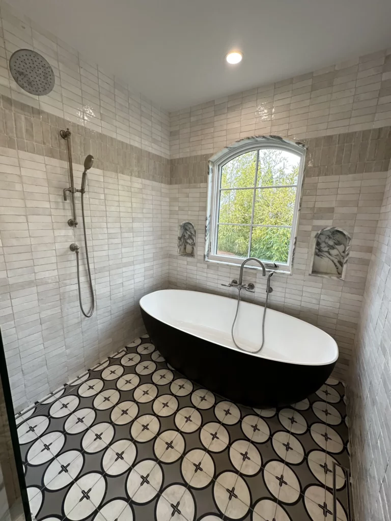 Modern bathroom with freestanding tub and geometric floor tiles.