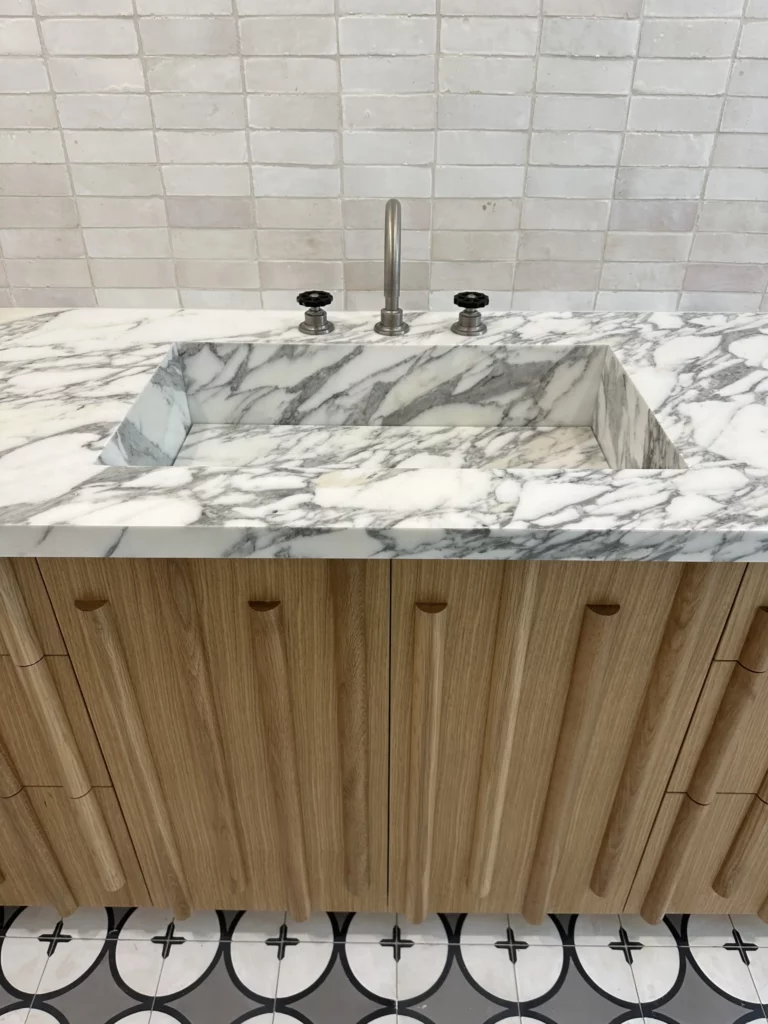 Marble countertop with modern kitchen sink and wooden cabinets.