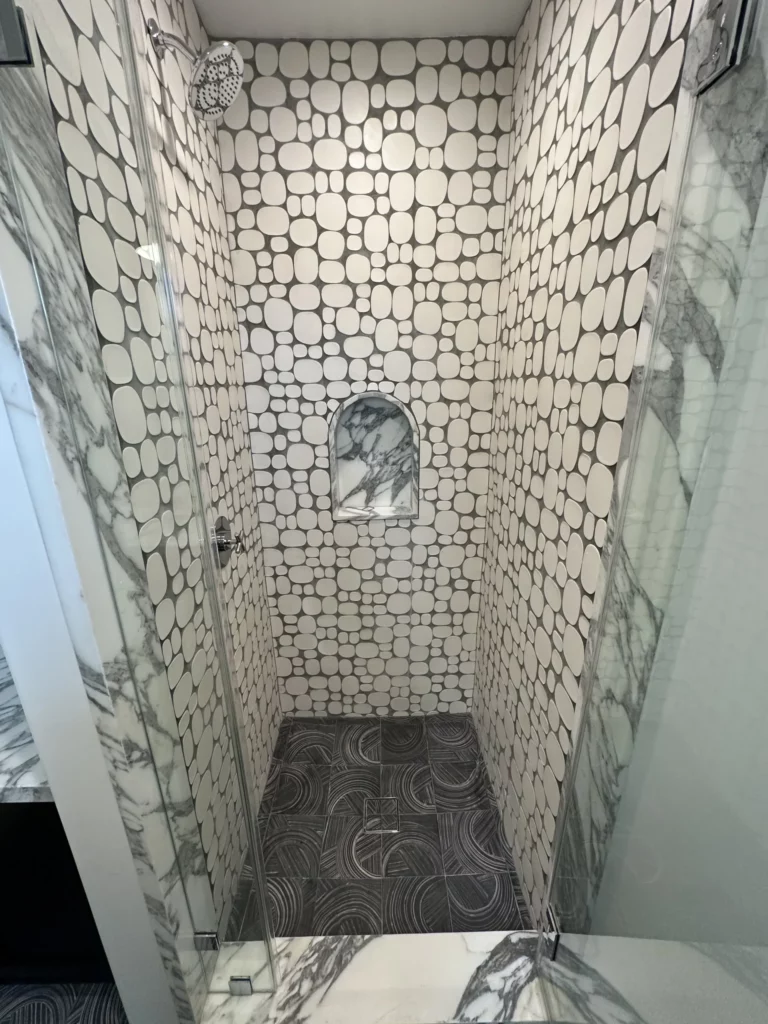 Modern bathroom with patterned tiles and glass door.
