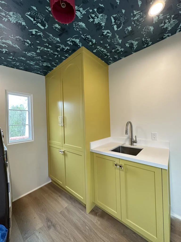 Modern kitchenette with yellow cabinetry and patterned ceiling.