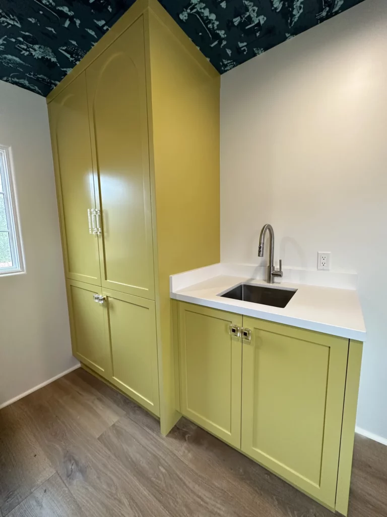 Modern yellow pantry cupboard and sink in kitchen.