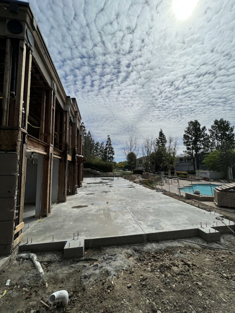 Construction site with new concrete foundation and cloudy sky.