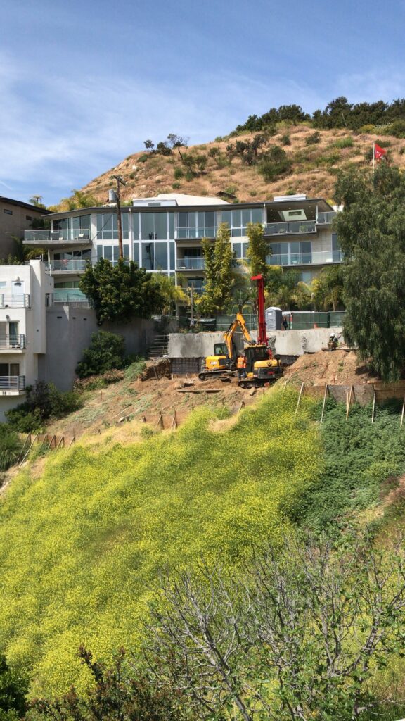 Construction site with excavators near hillside homes.