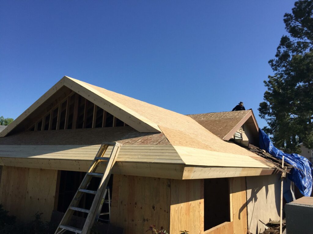 Roof construction with wooden trusses and partial sheathing.