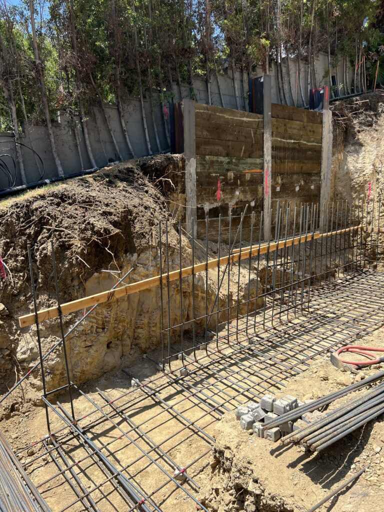 Construction site with excavated trench and reinforcement bars.