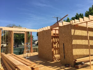 Wooden house framework construction site under clear sky.