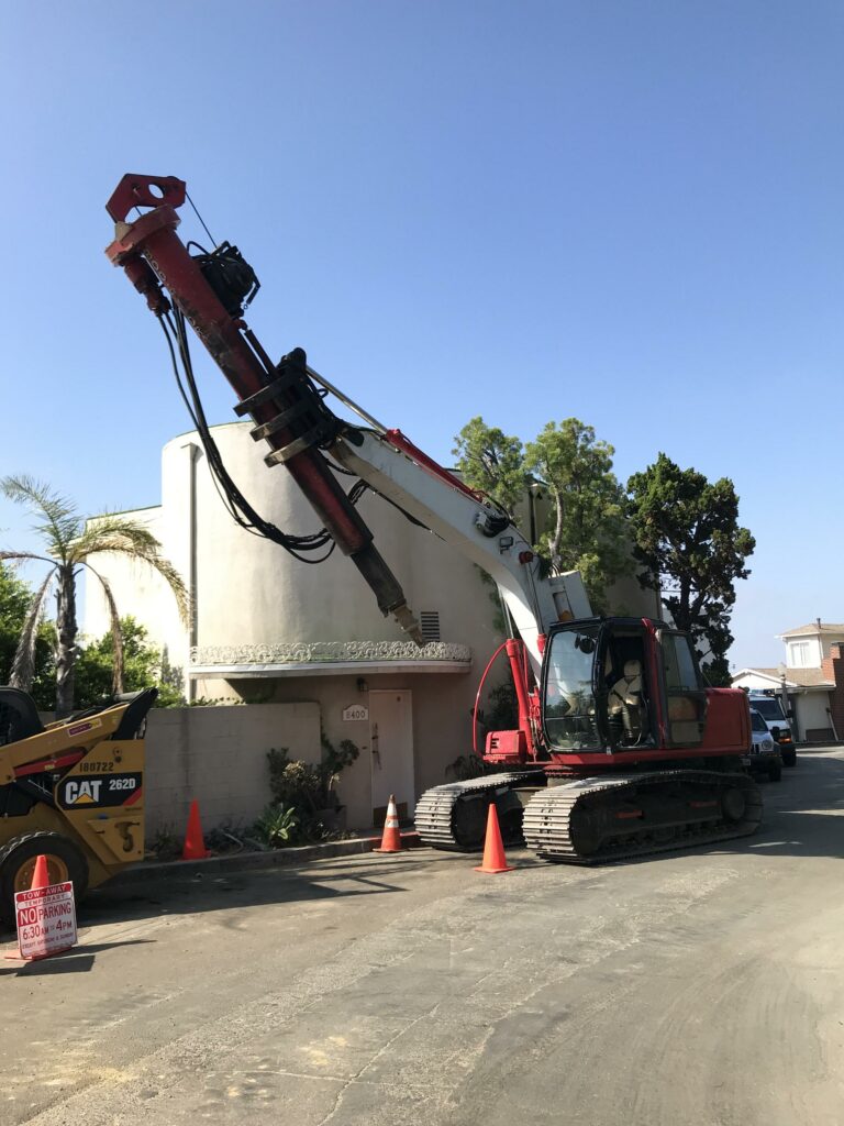 Excavator with hydraulic breaker outside building.