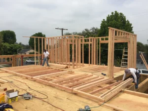 Construction workers building wooden house frame.