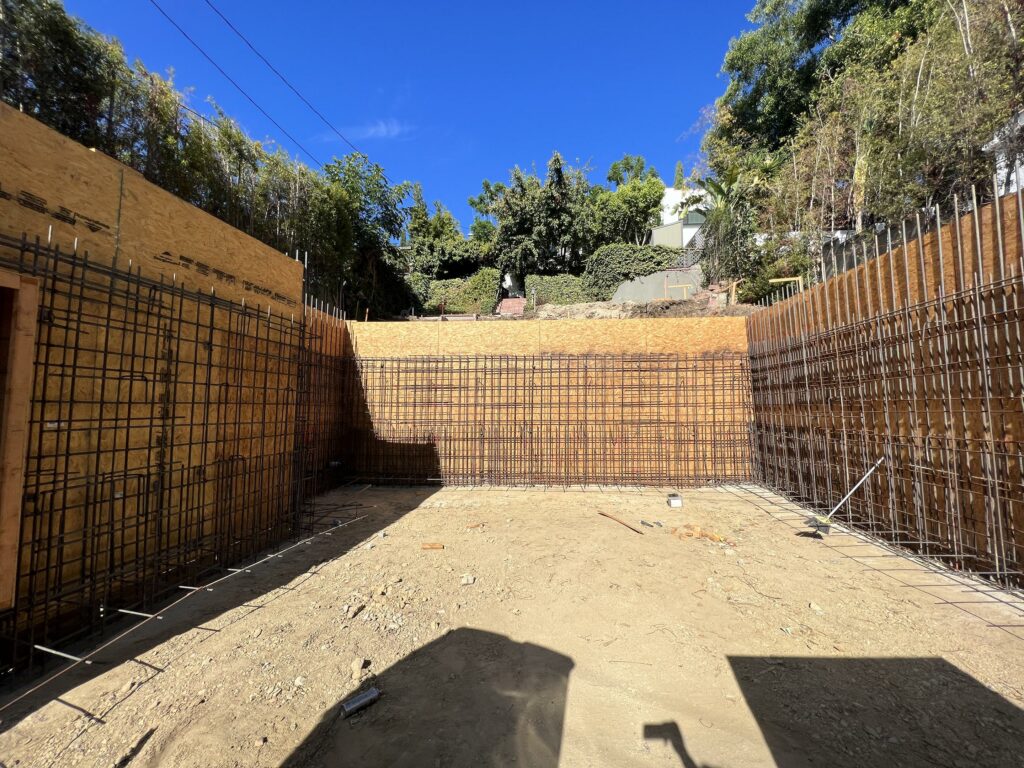 Construction site with steel rebar framework and retaining wall.