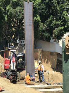 Construction workers installing a concrete pillar at a site.