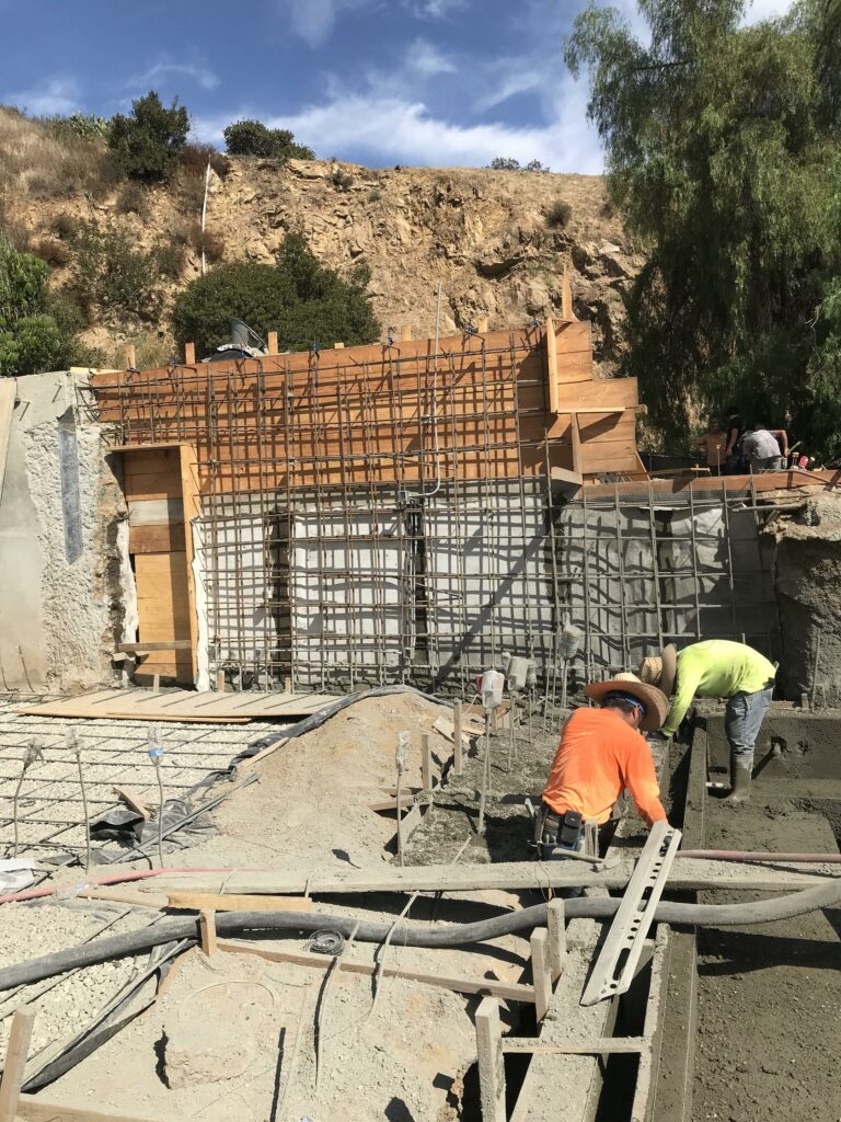Workers constructing concrete foundation at building site.