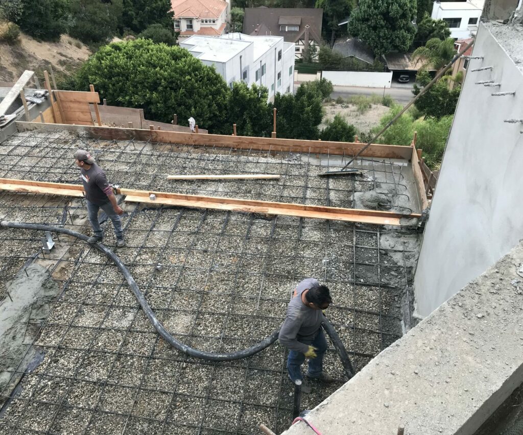 Workers preparing concrete foundation with reinforcement bars.