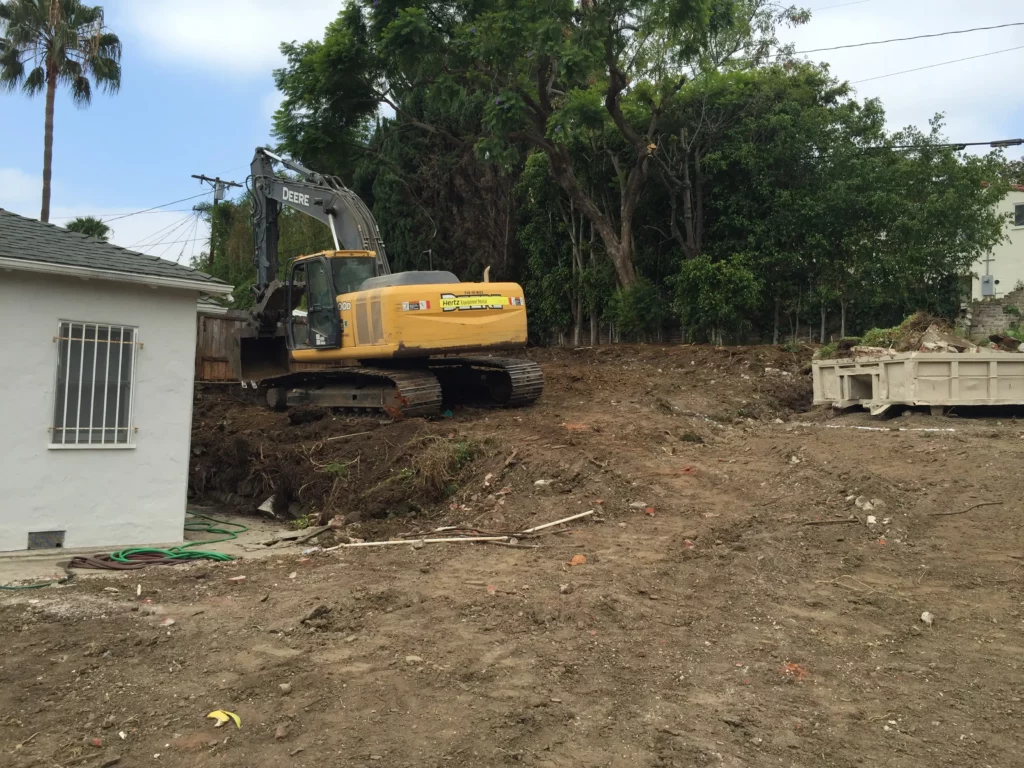 Excavator at residential construction site clearing land.