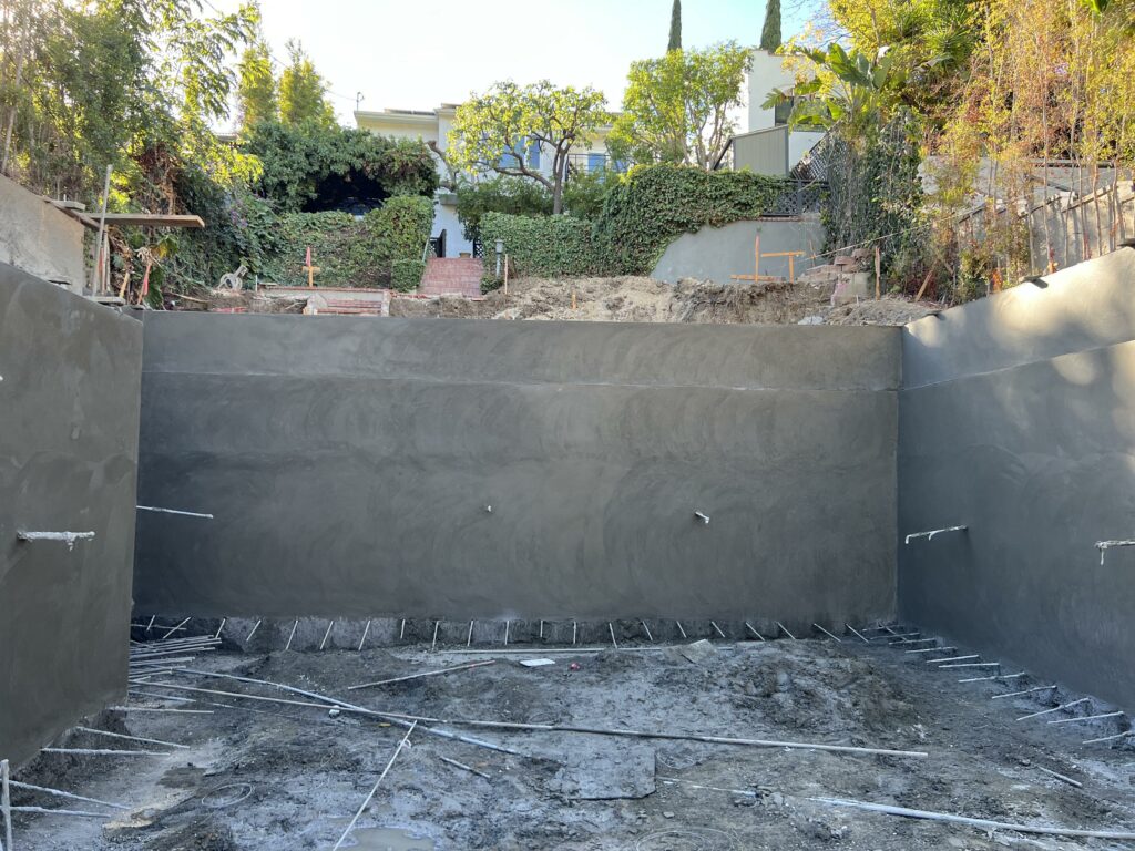 Construction site with unfinished pool and retaining walls.