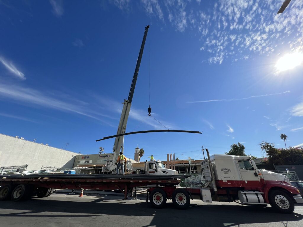 Crane lifting materials near truck on construction site