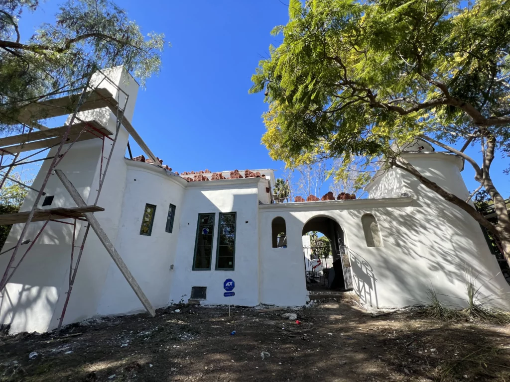 Renovation work on a white Spanish-style house with scaffolding.