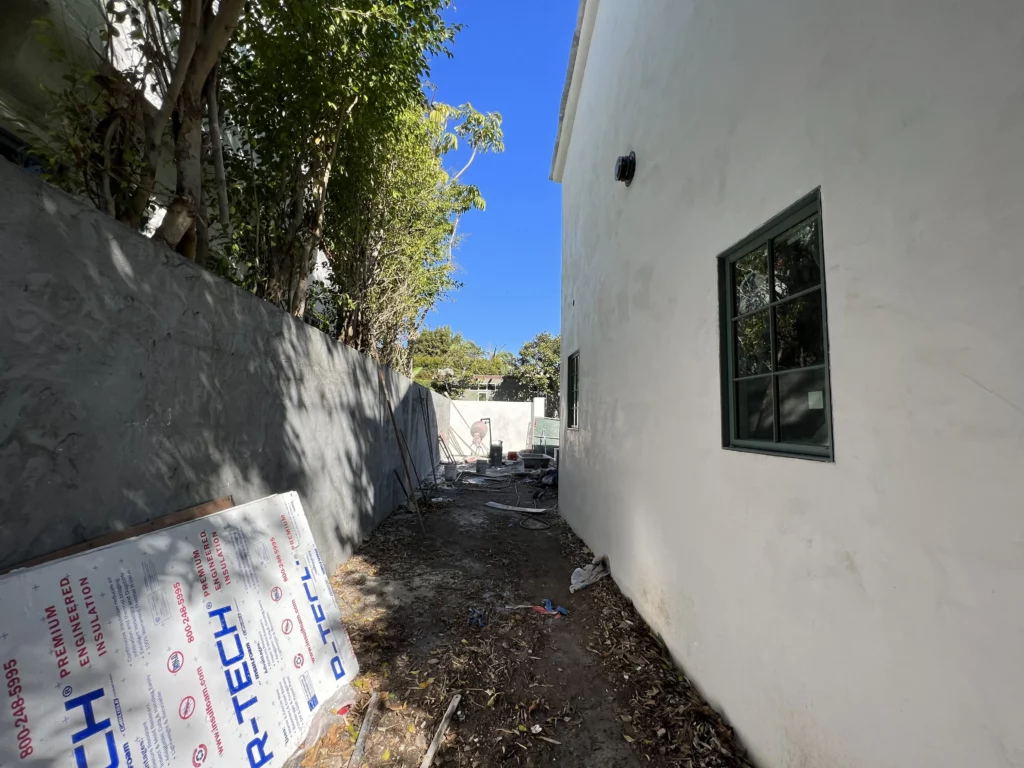 Narrow alley with construction materials beside white building.