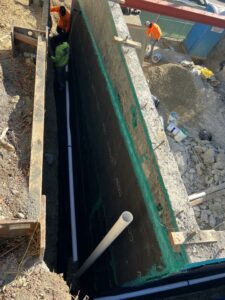 Workers installing underground pipes at construction site.