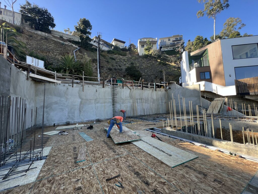 Worker at construction site with hillside homes.
