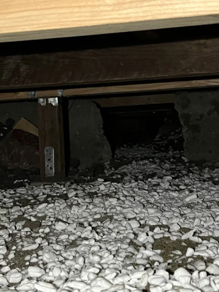 Crawlspace under house with white pebble covering.