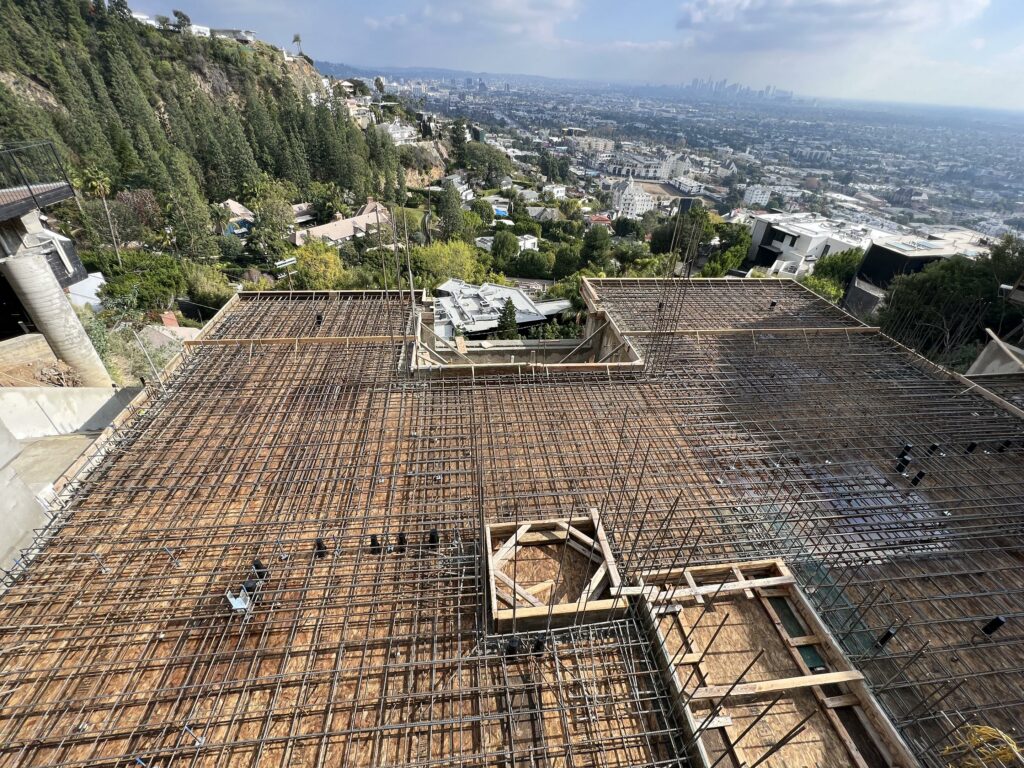 Construction site with rebar framework overlooking cityscape.