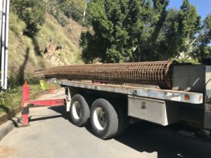 Flatbed truck hauling large rebar spool.