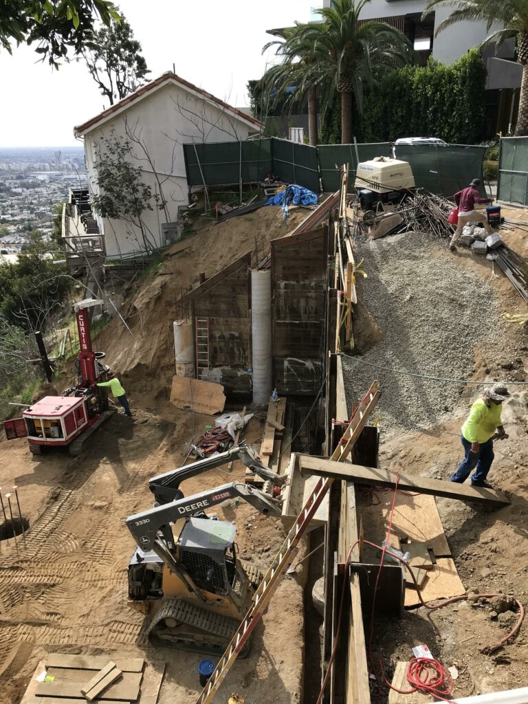 Hillside construction site with heavy machinery and workers.