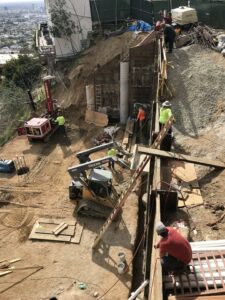 Construction workers on hillside building site with machinery.