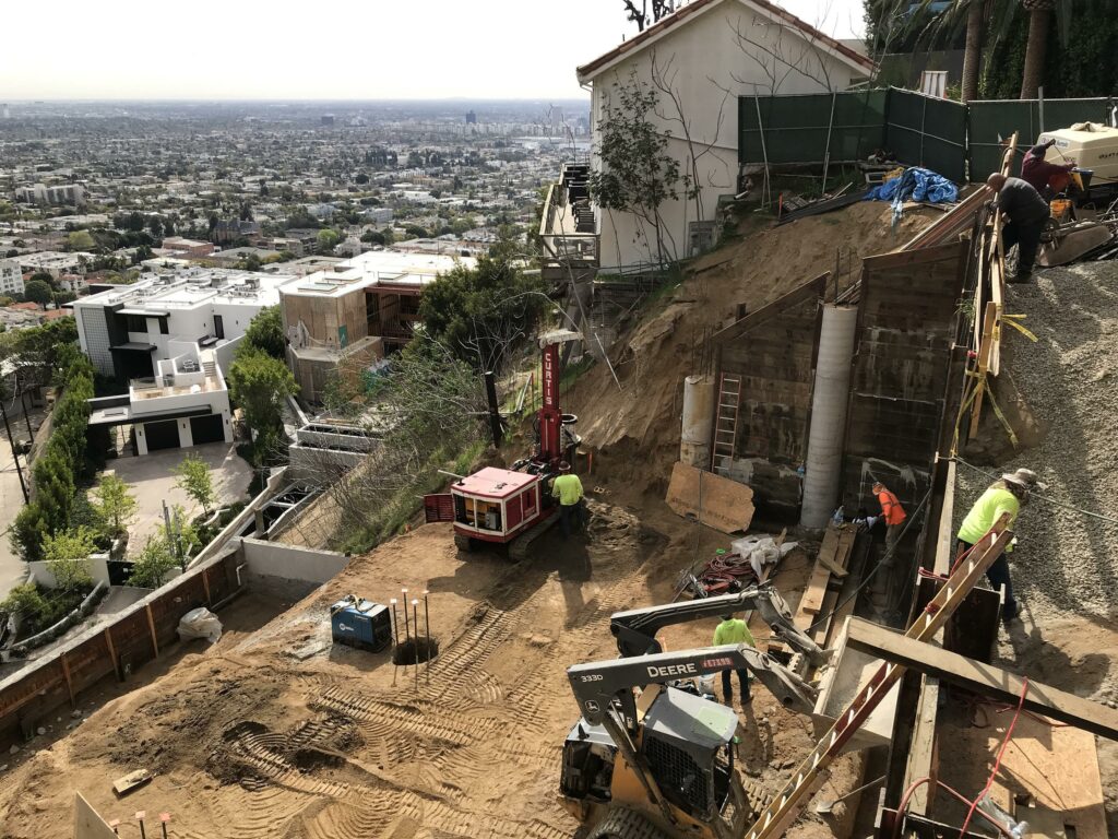 Hillside construction site with city view, heavy machinery, workers.