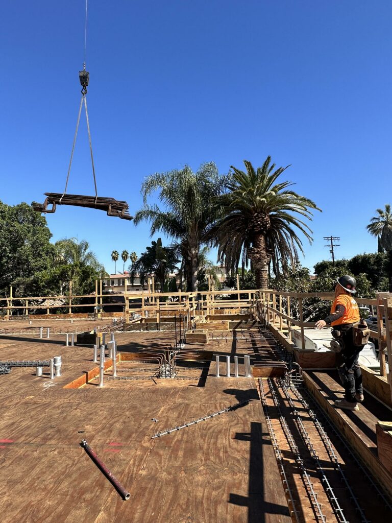 Construction site with crane, worker, and palm trees.