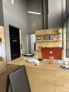 Modern office reception desk with computer and decor.